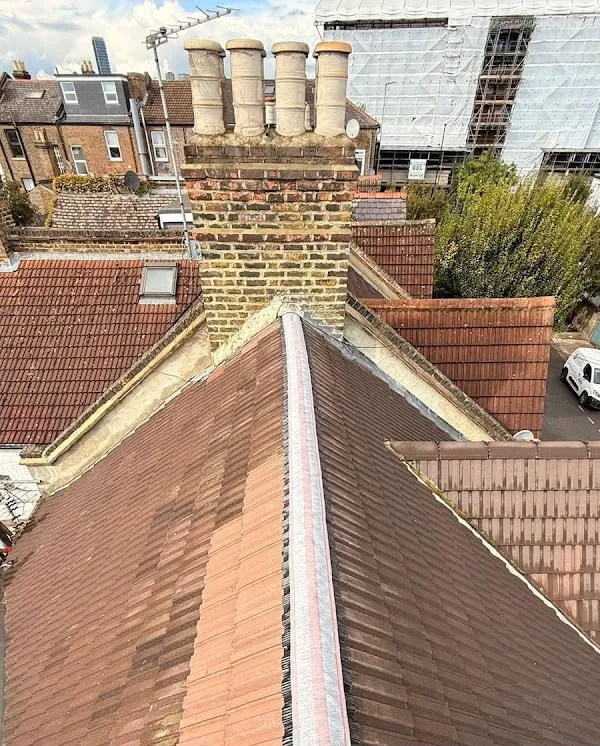 Re-tiled pitched roof beside brick chimney stacks