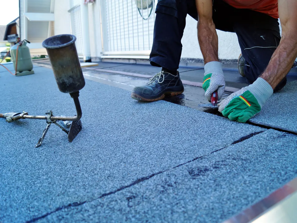 Roofer sealing a felt roof seam
