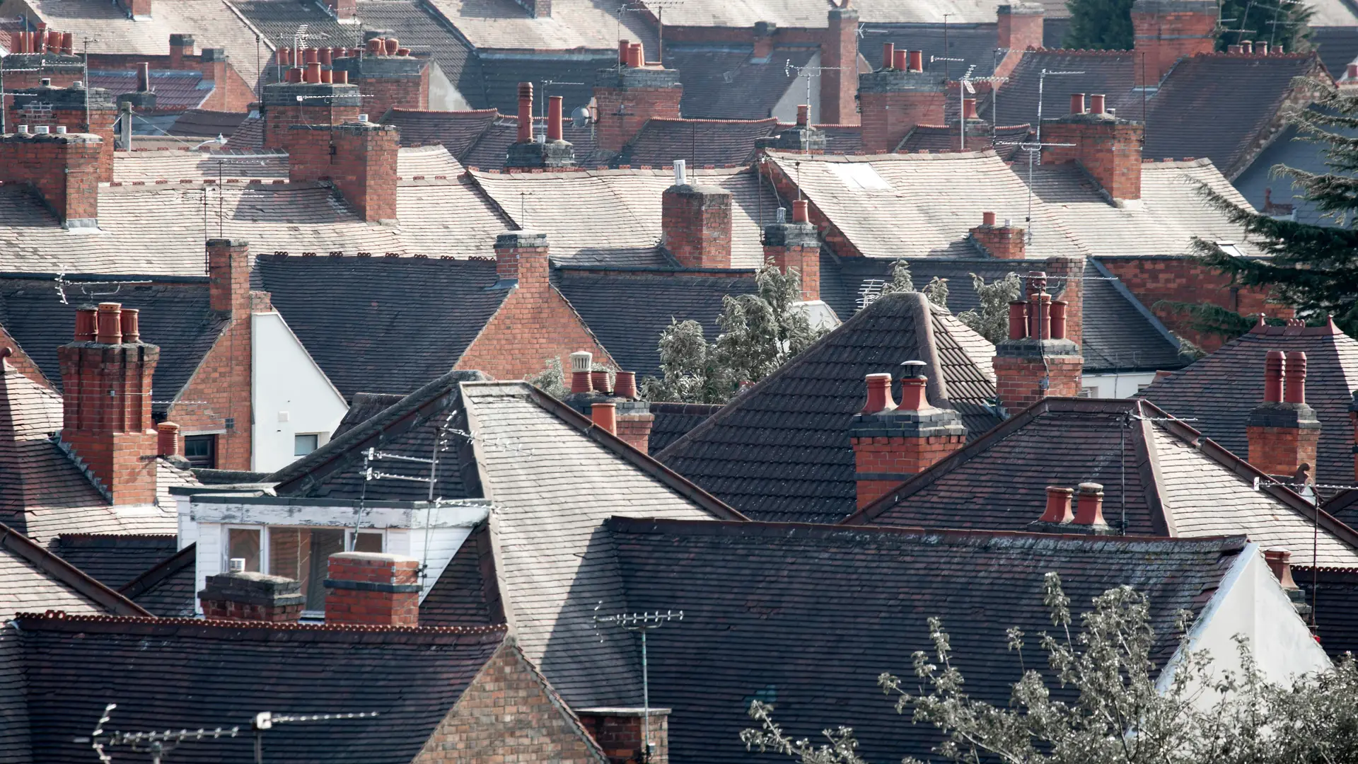 Rows of terraced house rooftops and brick chimneys