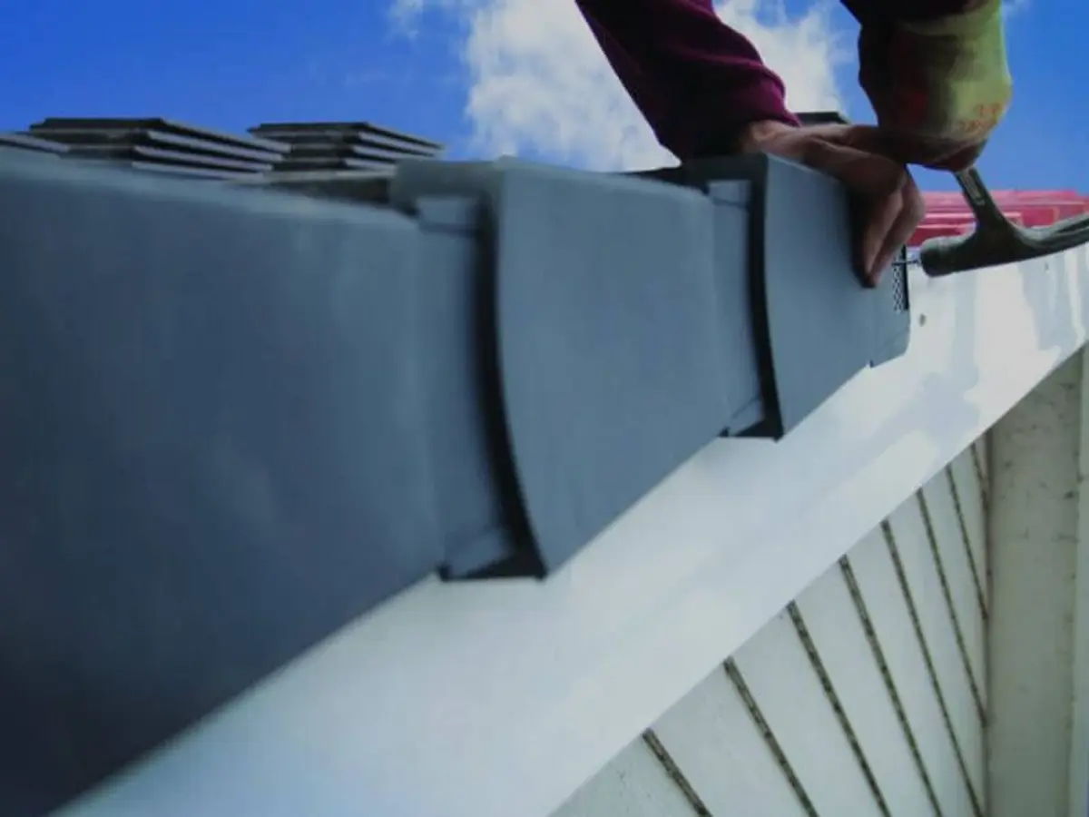 Roofer fitting a dry verge unit by hand