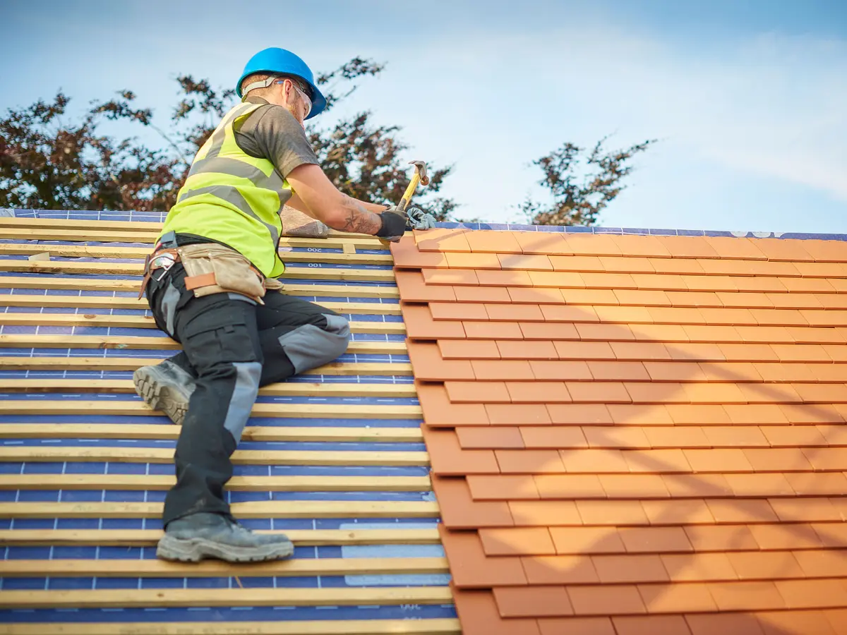 Roofer laying new clay plain tiles on a new roof