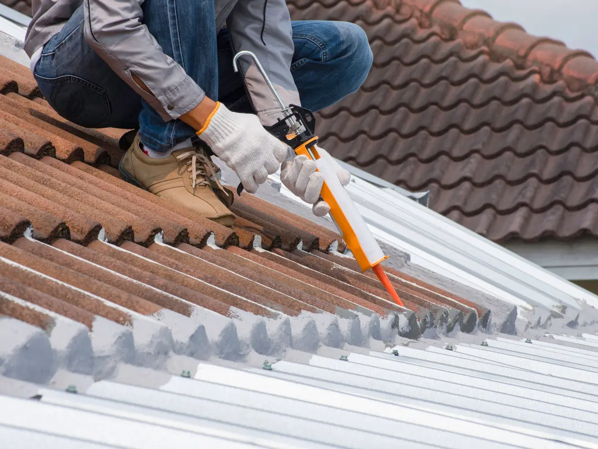 Roofer carrying out a roof repair with sealant