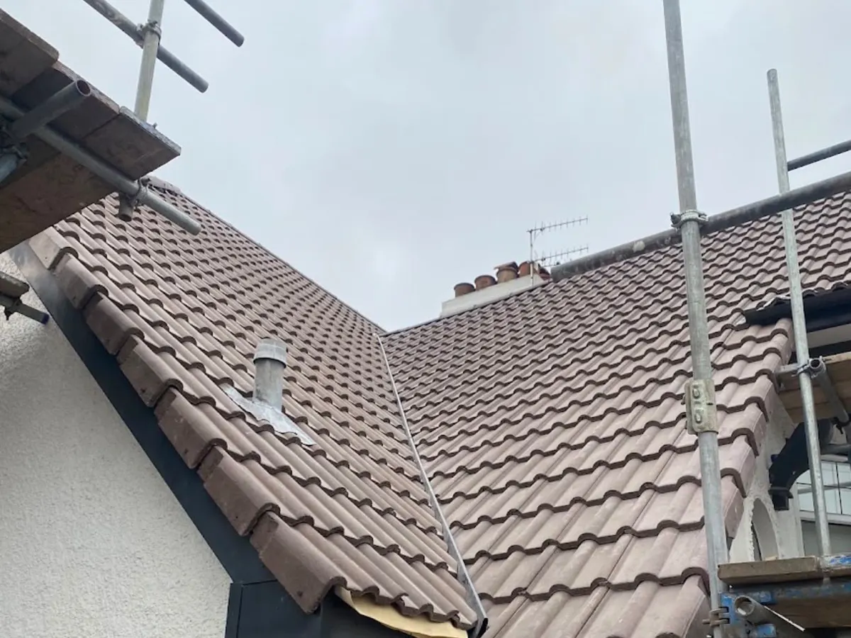 New tiled roof valley above fresh black fascias and guttering